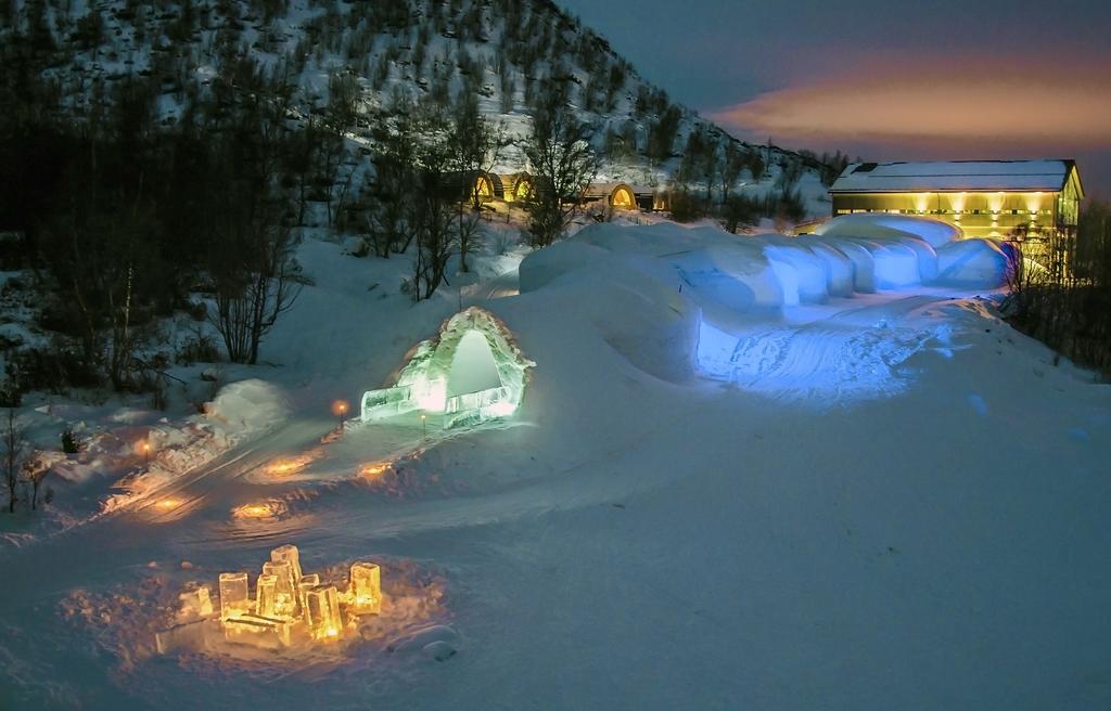 Snow rooms and timber service buildings beside a frozen fjord at Kirkenes